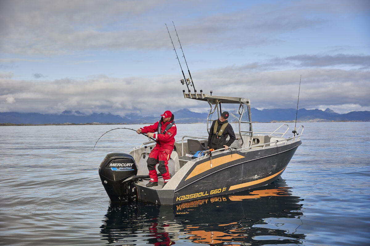 Står i båt og kjører stor fisk med fiskestang
